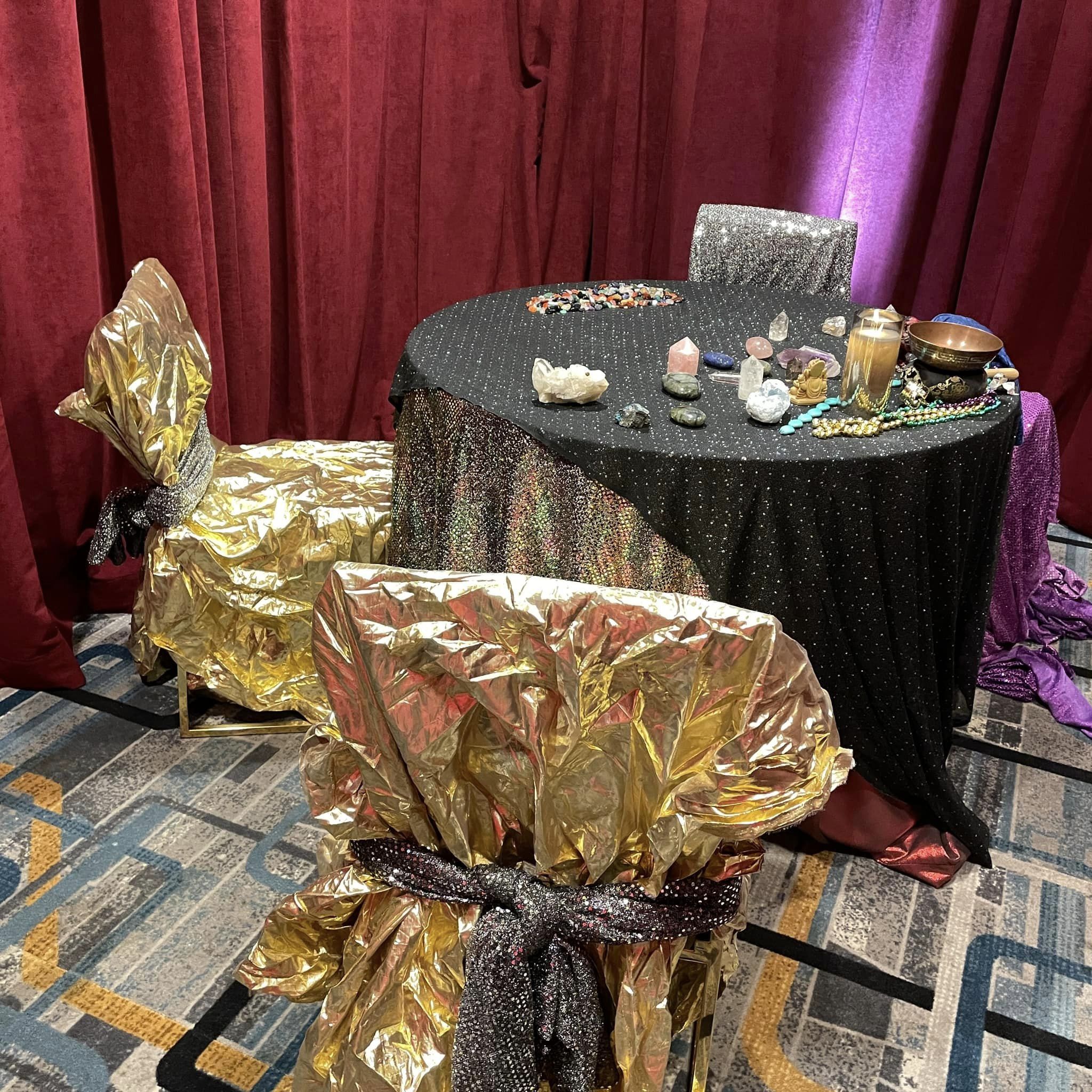 table covered in shiny black and gold cloths. sparkling gold chairs with crystals on the table